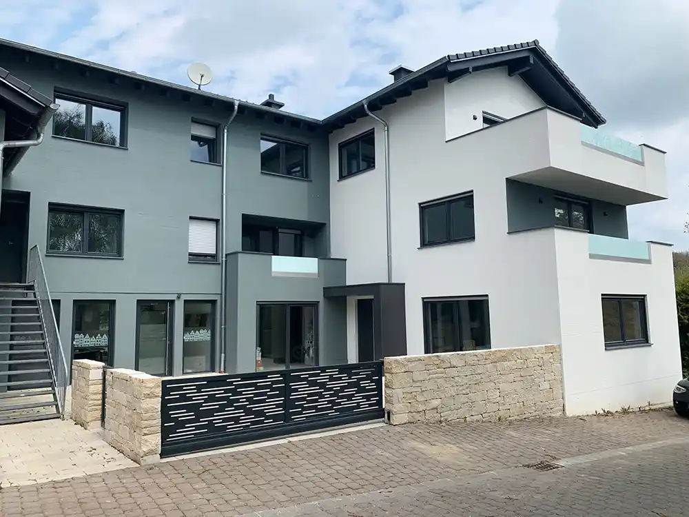 Blick auf eine Hauswand mit Fenstern und Balkon am Friedhofsweg1